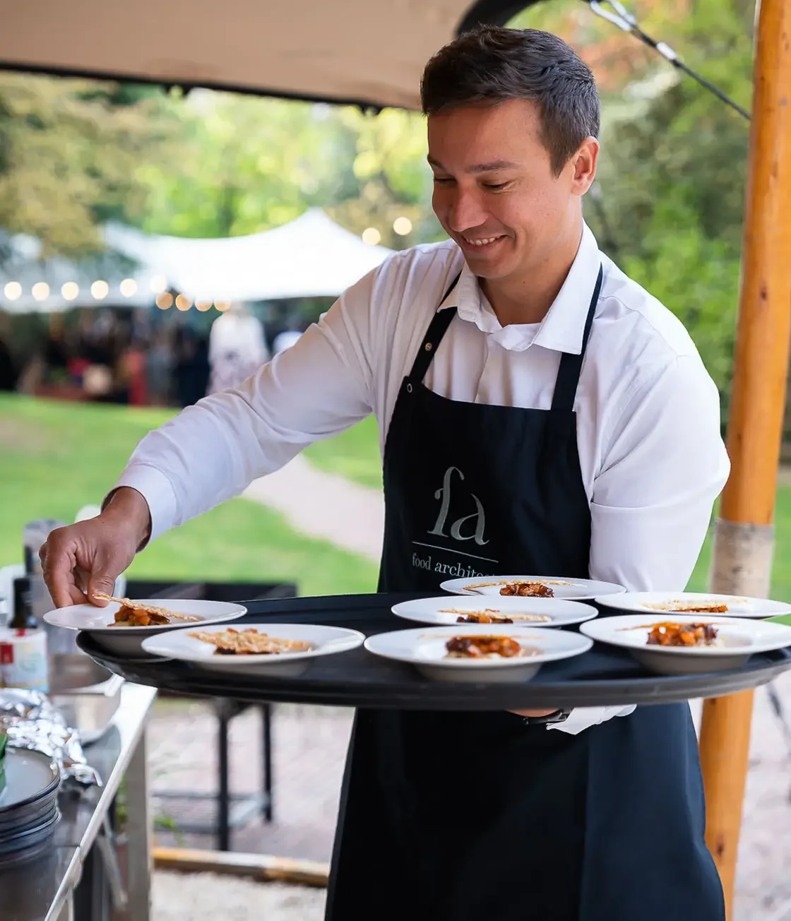 Medewerker met apron van Food Architect serveert een hapje