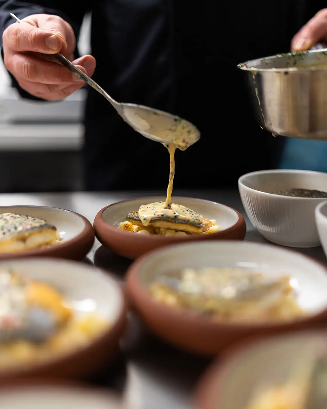 Chef werkt visgerechten af met saus